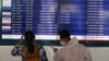 Para calon penumpang memperhatikan jadwal penerbangan yang dibatalkan di Bandara Internasional Soekarno-Hatta, 24 April 2020. (Foto: AP)