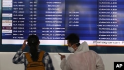 Para calon penumpang memperhatikan jadwal penerbangan yang dibatalkan di Bandara Internasional Soekarno-Hatta, 24 April 2020. (Foto: AP)