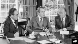 FILE - Then-vice presidential nominee Gerald R. Ford (R) listens as President Richard Nixon, accompanied by Secretary of State Henry Kissinger, speaks in the Oval Office of the White House in Washington, Oct. 13, 1973.