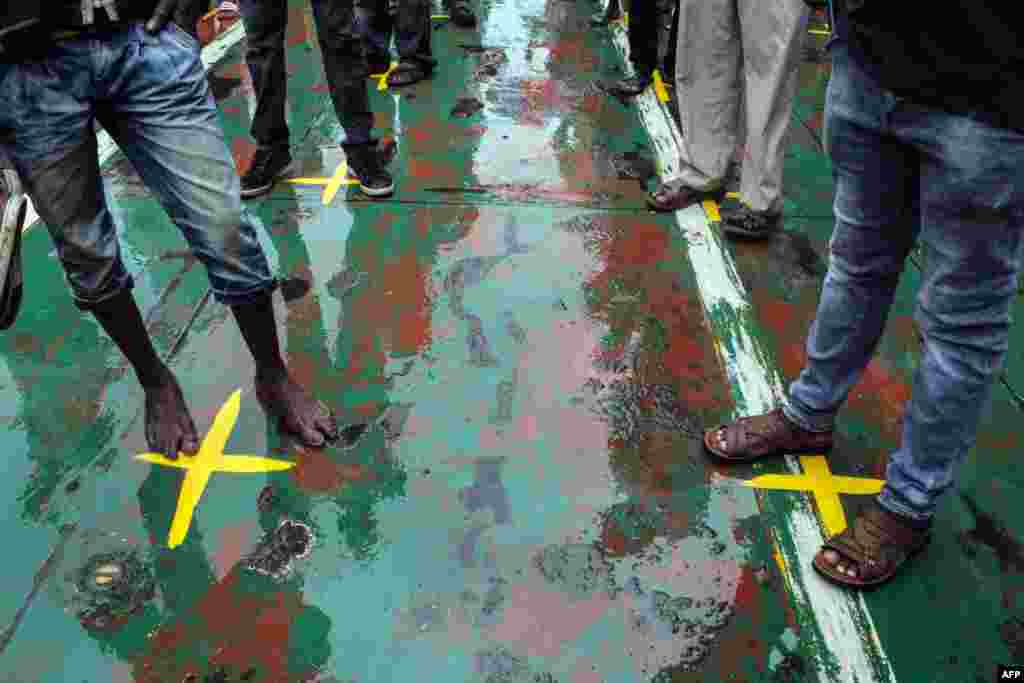 Commuters stand on yellow marks that indicate the physical distancing recommended to curb the COVID-19 coronavirus from spreading, on a ferry at Likoni ferry terminal, in Mombasa, Kenya. 