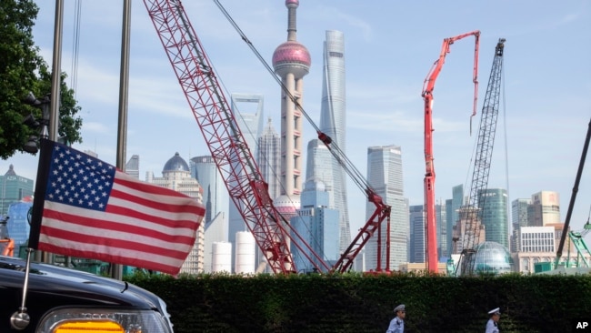 2019年7月30日星期二，中国上海交通警察走过一辆飘着美国国旗的大使馆汽车。