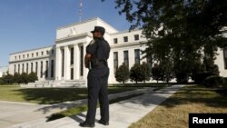 Seorang polisi untuk Federal Reserve berjaga-jaga di depan markas besar bank sentral Amerika ini, di Washington (16/9).