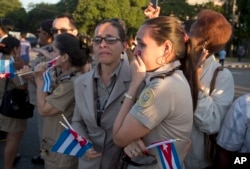 Officials from the costumes ministry react as , placed in a small coffin covered by a Cuban flag, the ashes of Cuban leader Fidel Castro are driven along Revolution Square in Havana, Cuba, Nov. 30, 2016.