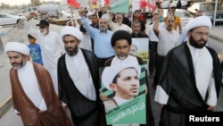 FILE - Protesters hold photos of Sheikh Ali Salman, Bahrain's main opposition leader and Secretary-General of Al-Wefaq Islamic Society, as they march asking for his release in the village of Jidhafs, west of Manama, Bahrain, June 16, 2015. 