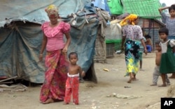 In this image made from video, March 18, 2017, Rosmaida Bibi, second from left, who suffers from severe malnutrition walks with the help of her mother Hamida Begum at the Dar Paing camp, north of Sittwe, Rakhine State, Myanmar.