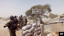 FILE - Cameroon soldiers stand guard at a lookout post as they take part in operations against the Islamic extremists group Boko Haram, their guard post is on Elbeid bridge, left rear, that separates northern Cameroon form Nigeria's Borno state, Feb. 25, 2015.