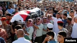 6月2日，约旦士兵和亲属在约旦首都安曼附近为在约叙边界哨所袭击事件中丧生的军人举行追悼会。图为这名军人的战友和家属抬着他的遗体。
