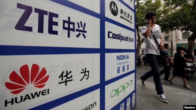 一名中国男子从武汉街头有着华为和中兴标徽的广告牌前走过。(资料照片)