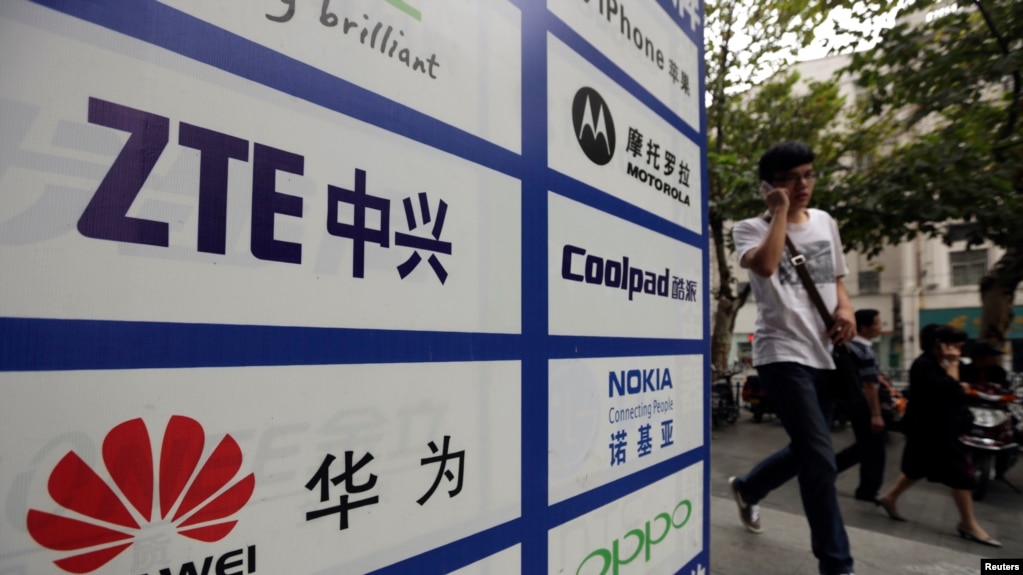 一名中国男子从武汉街头有着华为和中兴标徽的广告牌前走过。（资料照片）(photo:VOA)
