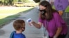 Asisten pengajar di Newton County Schools berbicara dengan siswa TK saat dia mengukur suhu tubuhnya di Decatur, Mississippi, Senin, 3 Agustus 2020. (Foto: AP)