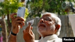 FILE - Hindu nationalist Narendra Modi, the prime ministerial candidate for India's main opposition Bharatiya Janata Party (BJP), takes a "selfie" with a mobile phone after casting his vote at a polling station during the seventh phase of India's general 