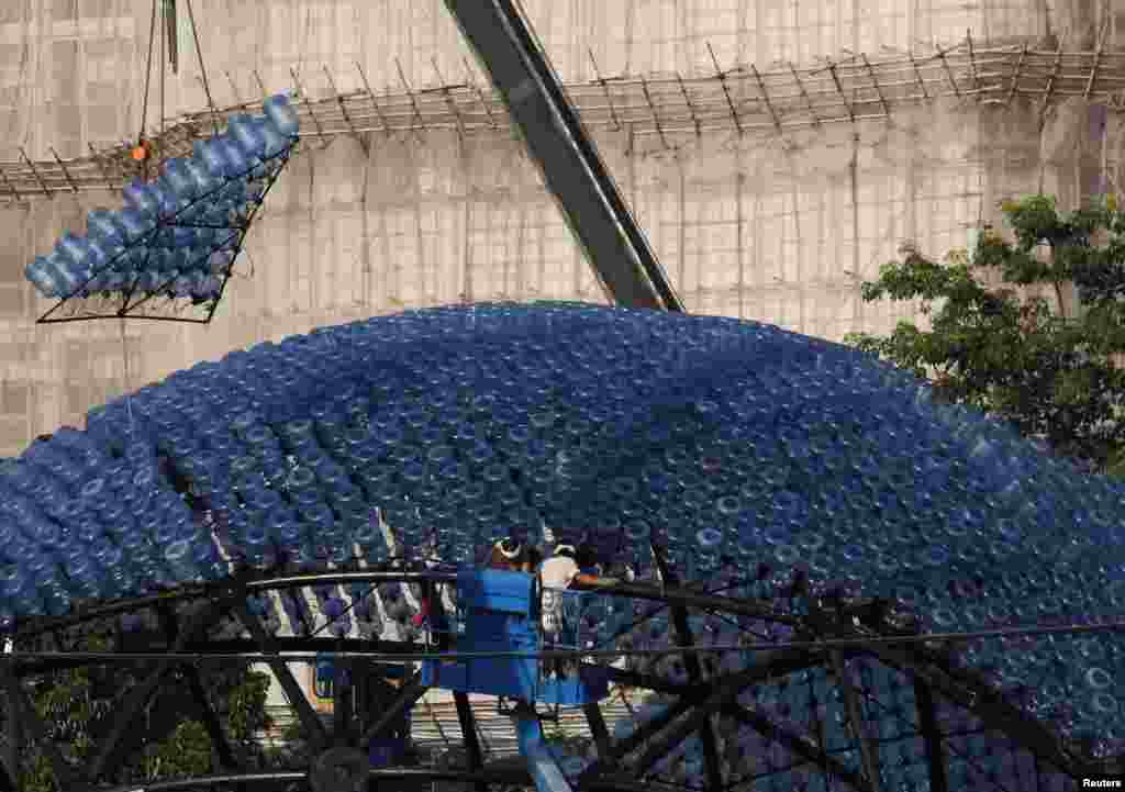 A segment to be assembled onto a sculpture containing 7,000 recycled plastic water bottles with LED lights, measuring 20 meters in diameter and 10 meters in height, is dangled from a crane at Hong Kong&#39;s Victoria Park. The &quot;Rising Moon&quot; is a giant lantern created to celebrate the upcoming Mid-Autumn Festival which falls on Sept.19.