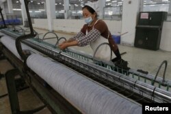 FILE - A worker disentangles wool yarn at a spinning machine at a factory owned by Hong Kong's Novetex Textiles Limited in Zhuhai City, Guangdong Province, China, Dec. 13, 2016.