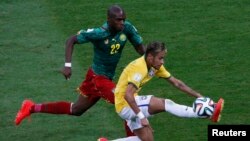 Pemain Kamerun Allan Nyom mengejar Neymar dari Brazil dalam pertandingan di stadion nasional Brasilia (23/6). 