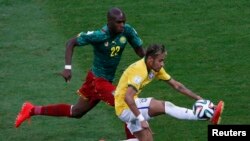 Brazil's Neymar, right, controls the ball in front of Cameroon's Allan Nyom during their match at the Brasilia national stadium in Brasilia, June 23, 2014.