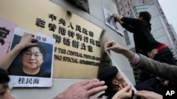FILE - Protesters try to stick photos of missing booksellers, one of which shows Gui Minhai, at left, during a protest outside the Liaison of the Central People's Government in Hong Kong, Jan. 3, 2016. 