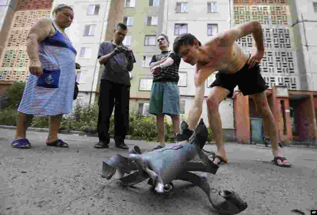 Local residents display a fragment of a shell after overnight shelling in Donetsk, eastern Ukraine, Aug. 8, 2014.