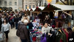 Shoppers look for gifts in booths set up for the holidays around City Hall in Philadelphia, Dec. 8, 2016. New numbers from a key data source show that shoppers are so far spending at a decent, but slightly slower pace this holiday season compared to last year.