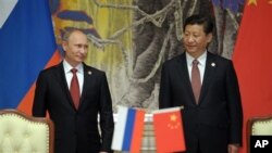 Le président de la Russie, Vladimir Poutine, et le président chinois Xi Jinping, sourient lors d'une cérémonie de signature d'un accord sur le gaz naturel entre leurs deux pays, à Shanghai, en Chine.