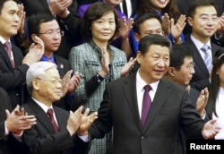 FILE - China's President Xi Jinping, front right, gestures to Vietnam's Communist Party General Secretary Nguyen Phu Trong as they pose for a group photo with Chinese and Vietnamese youths at the Great Hall of the People in Beijing, April 7, 2015.