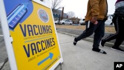 A sign, in Spanish and English, points the way to a vaccination clinic at City of Lawrence's "The Center," which serves seniors, families and the community, in Lawrence, Mass., Dec. 29, 2021.