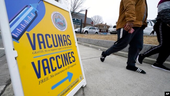A sign, in Spanish and English, points the way to a vaccination clinic at City of Lawrence's "The Center," which serves seniors, families and the community, in Lawrence, Mass., Dec. 29, 2021.