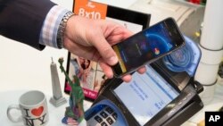 FILE - A customer makes a purchase with a MasterCard using Apple Pay on the iPhone 6 at Walgreens in New York's Times Square, Oct. 20, 2014.