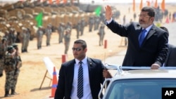 In this image released by the Egyptian Presidency, Egyptian President Mohammed Morsi, waves toward soldiers at a military base in Ismailia, Egypt, Oct. 10, 2012.