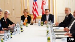 U.S. Secretary of State John Kerry, left, awaits the start of a meeting with Iranian Foreign Minister Mohammad Javad Zarif, second from right, after his return from Iran for international negotiations on nuclear policy in Vienna, Austria, June 30, 2015. 