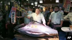 Kiyoshi Kimura, center, president of Kiyomura Co., poses with a bluefin tuna at his Sushi Zanmai restaurant near Tsukiji fish market in Tokyo, Jan. 5, 2017.