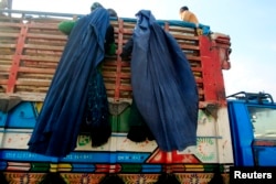 FILE - Afghan refugee women climb on a truck to be repatriated to Afghanistan, at the United Nations High Commissioner for Refugees (UNHCR) office on the outskirts of Peshawar, Feb. 13, 2015.