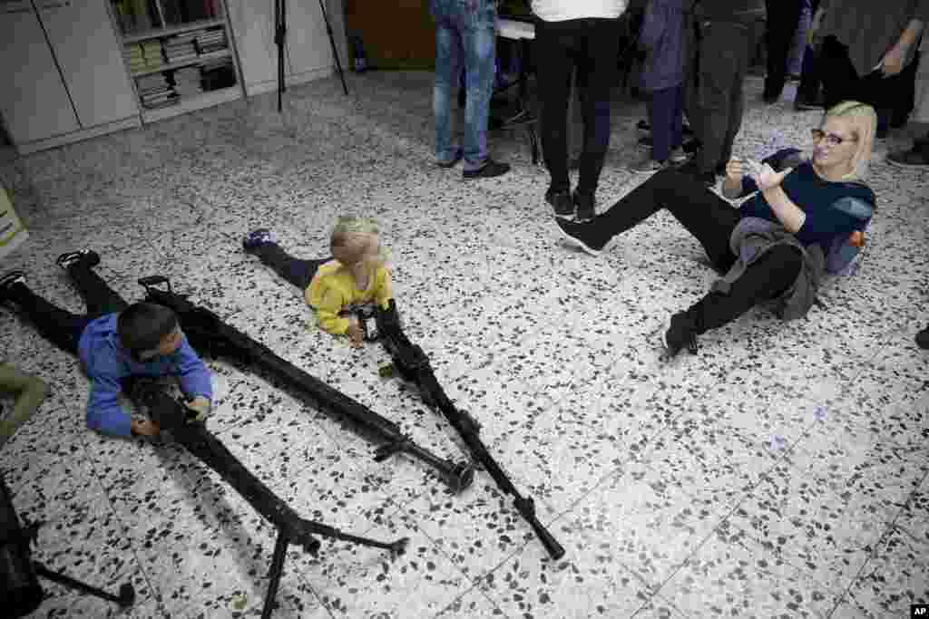 مادری درازکشیده روز زمین، سرگرم عکاسی از فرزندان نونهالش در پشت اسلحه های سنگین است. نمایشگاه اسلحه در شهر اِشدود اسرائیل در آستانه روز نهم مه یا &laquo;روز پیروزی&raquo; که یادآور شکست آلمان نازی است، برگزار شده است.