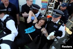 A climate change activist is detained during the Extinction Rebellion protest on Waterloo Bridge in London, April 20, 2019.