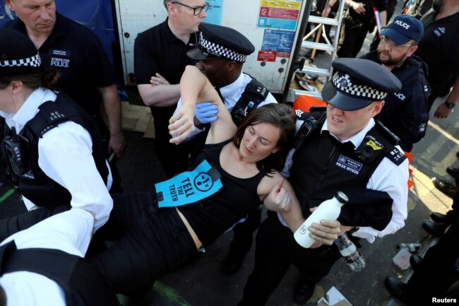 A climate change activist is detained during the Extinction Rebellion protest on Waterloo Bridge in London, April 20, 2019.