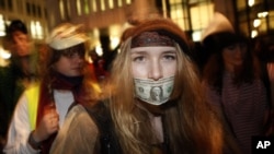 A woman dances with a US dollar covering her mouth during a protest against government austerity measures in central London November 30, 2011.