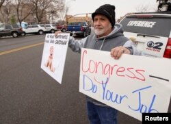 U.S. Internal Revenue Services employee holds signs in front of the federal building at a rally against the ongoing U.S. federal government shutdown, in Ogden, Utah, Jan. 10, 2019.