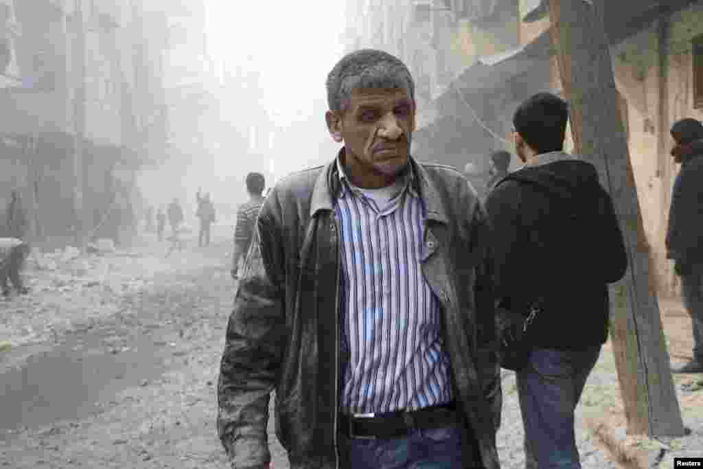 A man walks at a site hit by what activists said was a barrel bomb dropped by forces loyal to Syria&#39;s President Bashar al-Assad in Aleppo&#39;s al-Shaar district. 