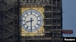 FILE - Workers stand on scaffolding underneath one of the clock faces on the Elizabeth Tower, more commonly known as Big Ben, as renovation works continue at the Houses of Parliament, London, Britain, September 6, 2021. (REUTERS/Toby Melville/File Photo)
