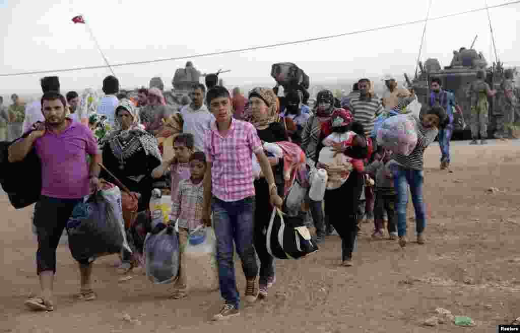 Syrian Kurds walk with their belongings after crossing into Turkey at the Turkish-Syrian border, near the southeastern town of Suruc in Sanliurfa province, September 20, 2014. About 60,000 Syrian Kurds fled into Turkey in the space of 24 hours, a deputy p