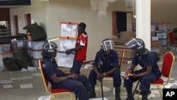 Zambian police sits at the Civic Center in Lusaka, Zambia, as election volunteers carry ballot boxes, September 22, 2011.