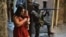 A woman walks with her baby past a PM militarized police soldier in position and aiming his rifle in Rocinha favela in Rio de Janeiro, Brazil on September 23, 2017. 