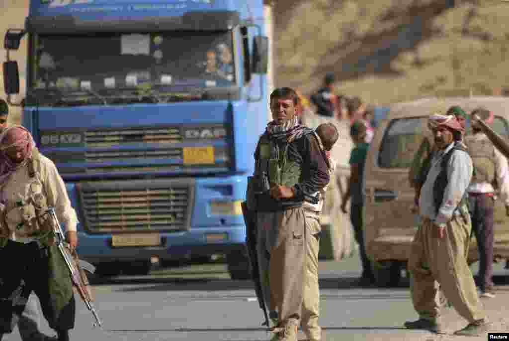 Yazidi fighters who recently joined the Kurdish People's Protection Units (YPG) secure a road in Mount Sinjar in northern Iraq, which is used by displaced people from the Yazidi religious minority fleeing violence from forces loyal to the Islamic State in