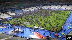 Para penonton memenuhi lapangan di stadion Stade de France tempat timnas Perancis bertanding melawan Jerman, setelah ledakan di luar stadion, Jumat malam (13/11).