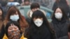 FILE - Commuters wearing masks make their way amid thick haze in the morning in Beijing. China's north is suffering a pollution crisis, with the capital Beijing itself shrouded in acrid smog. Authorities have introduced anti-pollution policies.