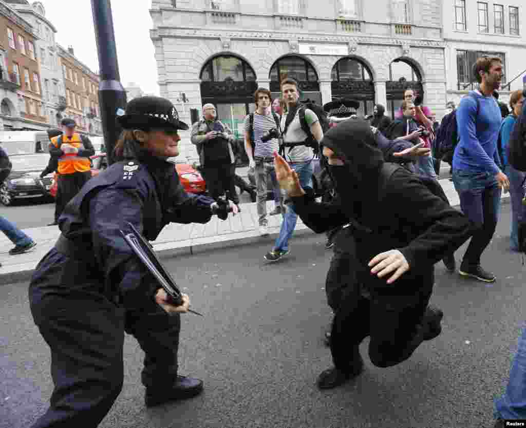 A protester demonstrating against the upcoming G8 summit tries to evade a police officer in central London, June 11, 2013. Police in riot gear moved in on a building in London's Soho district where activists had planned an anti-G8 protest through the British capital, before next week's summit of world leaders in Enniskillen, Northern Ireland.