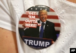 FILE - A supporter of Republican presidential candidate Donald Trump wears a campaign button before the start of a rally in Spokane, Wash.