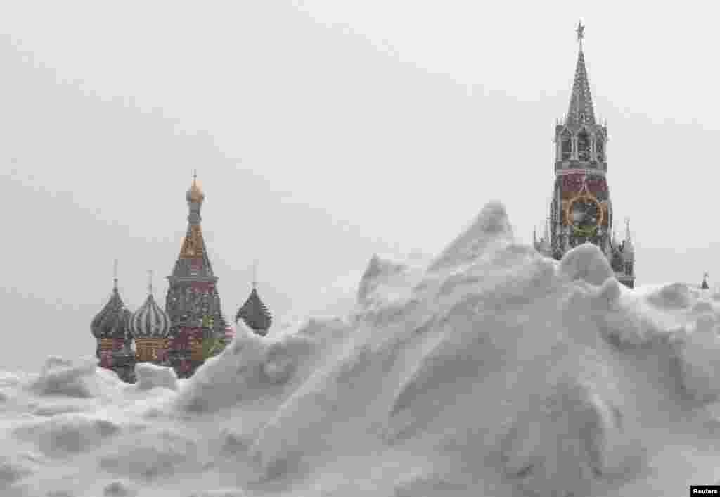 Tumpukan salju terlihat di Lapangan Merah selama hujan salju di pusat kota Moskow. Gereja Katedral St Basil (kiri) dan Menara Spasskaya Kremlin terlihat di latar belakang.