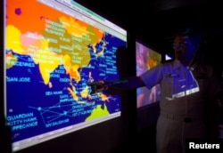 United States Navy Lieutenant Commander Kirk Benson, points at a map of the South China sea at the Tactical Flag Command Center (TFCC) of the 19,200-ton USS Blue Ridge in Manila, July 22, 2014.