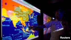 FILE - United States Navy lieutenant commander Kirk Benson, points at a map of the South China sea at the Tactical Flag Command Center (TFCC) of the 19,200-ton USS Blue Ridge in Manila, July 22, 2014.