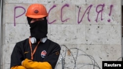 A masked pro-Russia protester stands guard at a barricade outside a regional government building in Donetsk, eastern Ukraine on April 19, 2014.